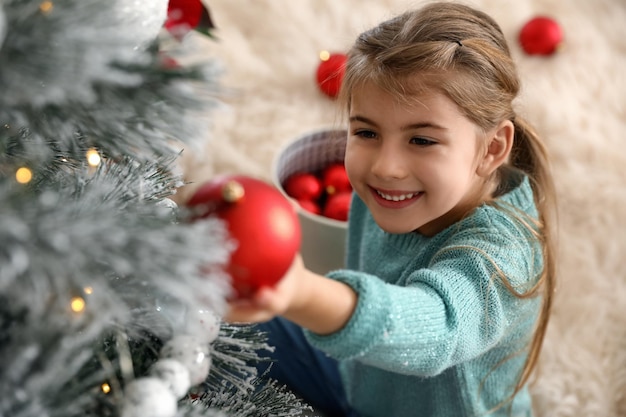 Bambina sveglia che decora l'albero di Natale a casa sopra la vista