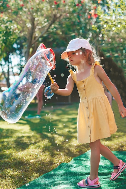 Bambina sveglia che fa bolla di sapone molto grande