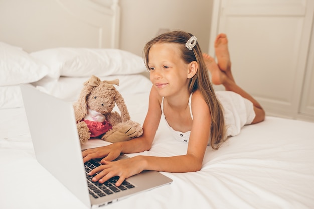 Bambina sveglia che fa i compiti sul computer portatile