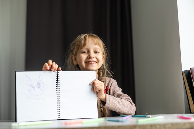 Bambina sveglia che fa i suoi compiti, primo piano, sullo sfondo interno della casa