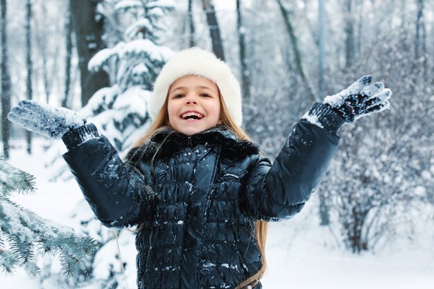 Bambina sveglia che gioca con la neve nel parco invernale