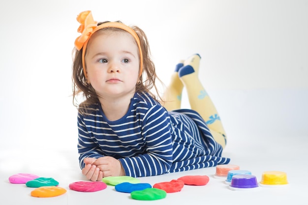 Bambina sveglia che gioca con la plastilina colorata su sfondo bianco