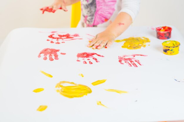 Bambina sveglia che gioca con le pitture colorate su una priorità bassa bianca