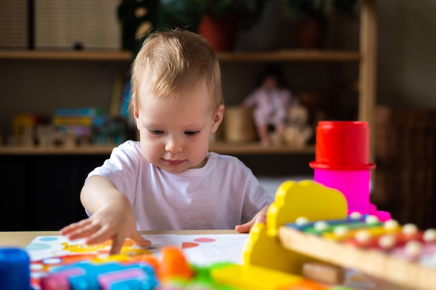 Bambina sveglia che gioca da solo con molti giocattoli di plastica colorati a casa.