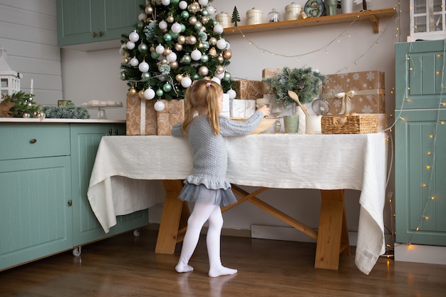 Bambina sveglia che gioca nella cucina di natale