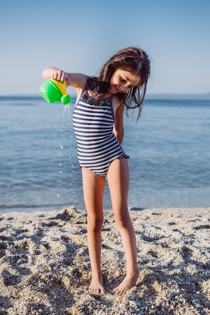 Bambina sveglia che gioca sulla spiaggia