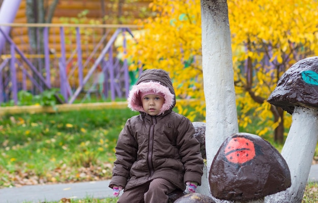 Bambina sveglia che guarda l'obbiettivo nel parco d'autunno