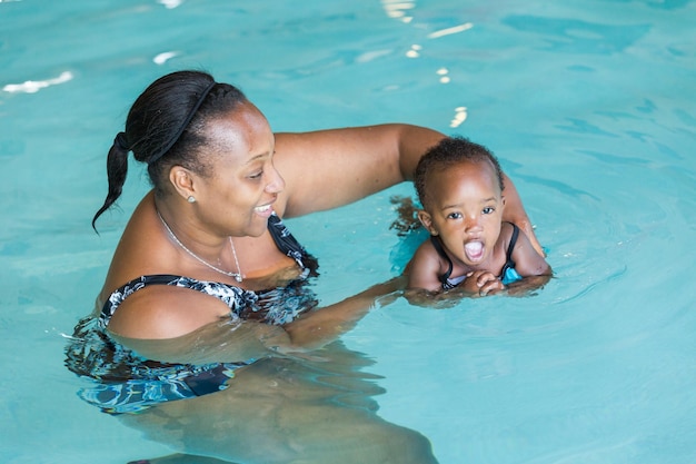 Bambina sveglia che impara a nuotare nella piscina coperta.