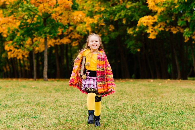 Bambina sveglia che legge un libro nel parco d'autunno