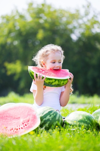 Bambina sveglia che mangia anguria sull'erba in estate Cibo sano per bambini