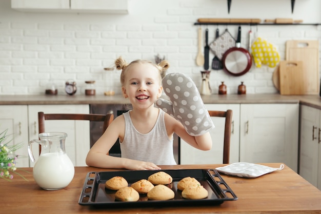 Bambina sveglia che mangia i biscotti appena sfornati in cucina. Famiglia felice. Tonificante.