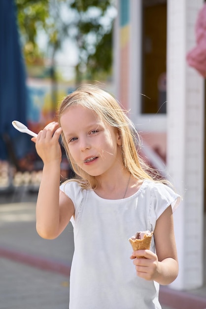 Bambina sveglia che mangia il gelato fuori Il fuoco è sulla ragazza in primo piano