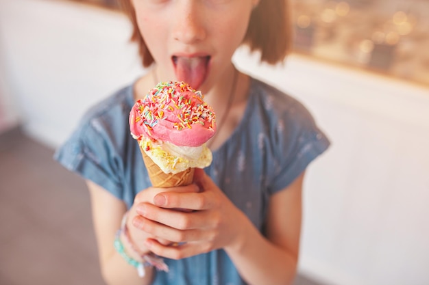 Bambina sveglia che mangia il gelato nella caffetteria Bambino che tiene il gelato Kid e dolci