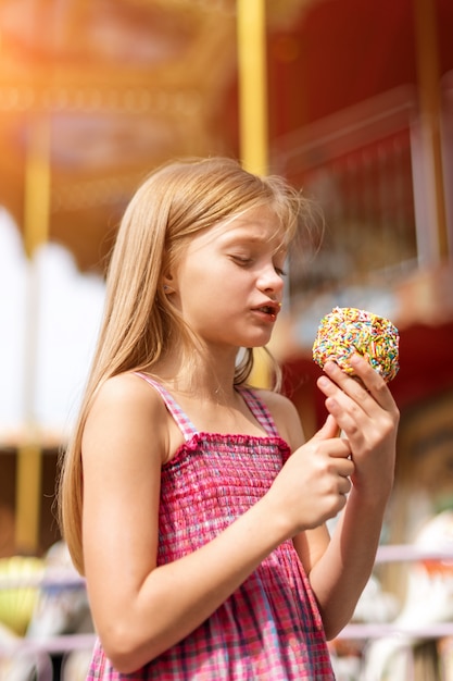 Bambina sveglia che mangia la mela di caramella ad una fiera