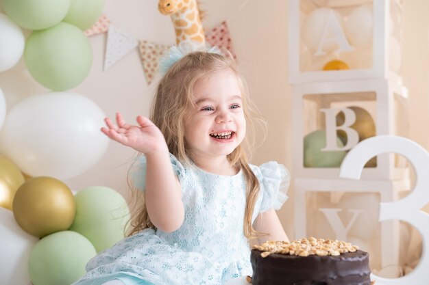 Bambina sveglia che mangia la torta di compleanno al cioccolato e festeggia il compleanno