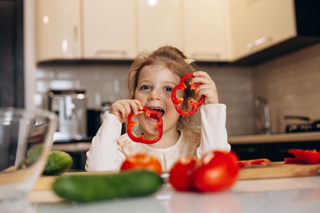 Bambina sveglia che prepara insalata dal peperone dolce fresco