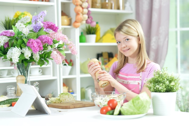 Bambina sveglia che prepara insalata fresca