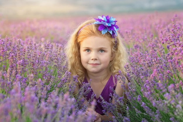 Bambina sveglia che si siede al prato della lavanda