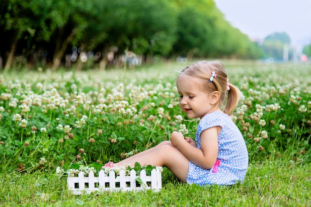 Bambina sveglia che si siede su un campo di trifoglio