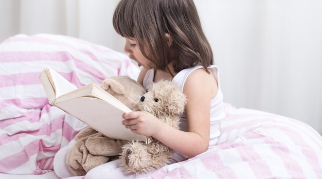 Bambina sveglia che sorride mentre giaceva in un accogliente letto bianco