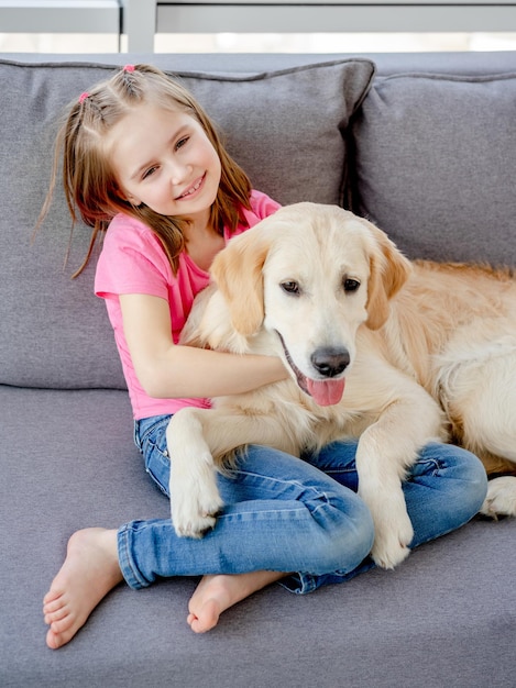 Bambina sveglia che stringe a sé il cane giocoso a casa