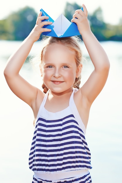 Bambina sveglia che tiene barca origami all'aperto