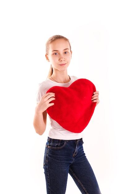 Bambina sveglia che tiene cuore rosso isolato. San Valentino, concetto di amore e felicità.