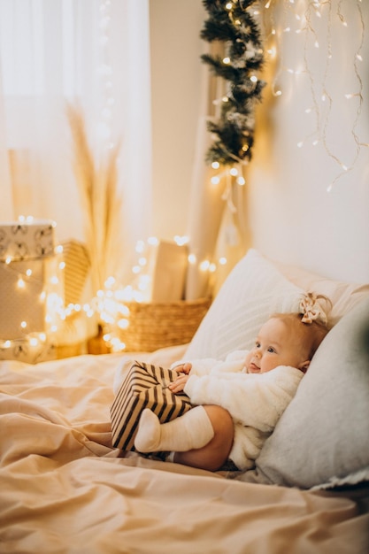 Bambina sveglia che tiene il regalo di Natale sul letto