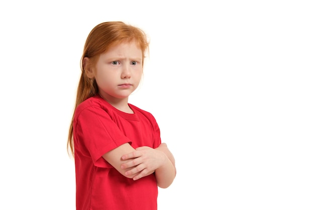 Bambina sveglia con i capelli rossi e le braccia piegate che sembrano sfondo bianco isolato arrabbiato