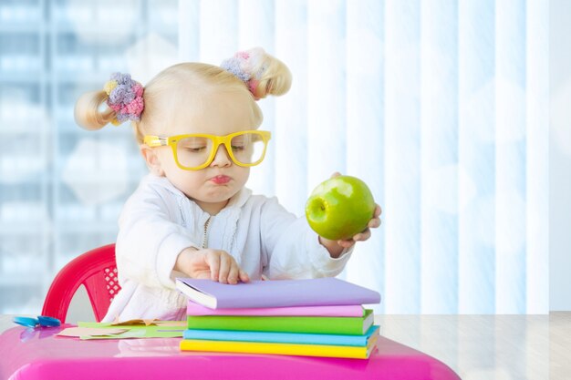 Bambina sveglia con i libri e la mela verde