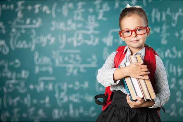 Bambina sveglia con i libri sullo sfondo