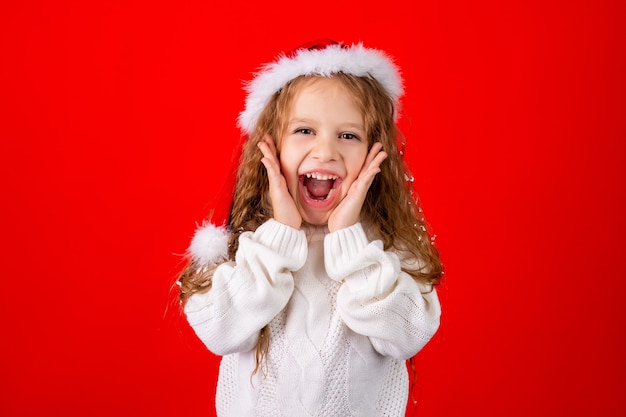 Bambina sveglia con il cappello di Babbo Natale e un maglione