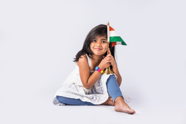 Bambina sveglia con la bandiera tricolore nazionale indiana, isolata sopra fondo bianco. Adatto per il concetto di Festa dell'Indipendenza o Festa della Repubblica