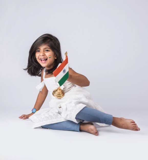 Bambina sveglia con la bandiera tricolore nazionale indiana, isolata sopra fondo bianco. Adatto per il concetto di Festa dell'Indipendenza o Festa della Repubblica