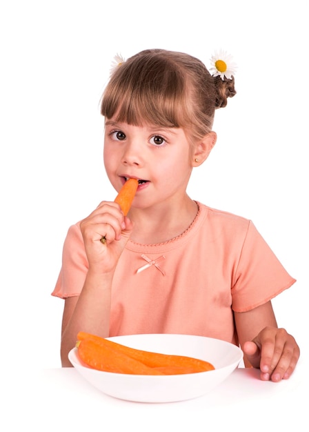 Bambina sveglia con la carota su sfondo bianco