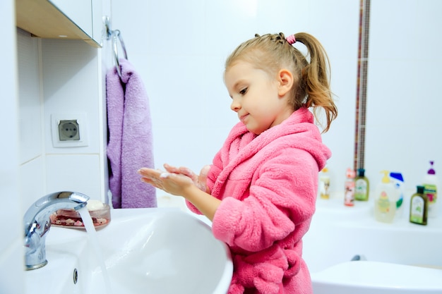 Bambina sveglia con la coda di cavallo in accappatoio rosa