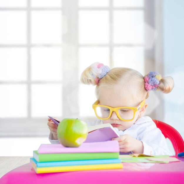 Bambina sveglia con la mela verde e i libri variopinti