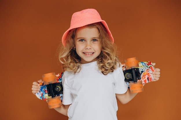 Bambina sveglia con lo skateboard isolato in studio