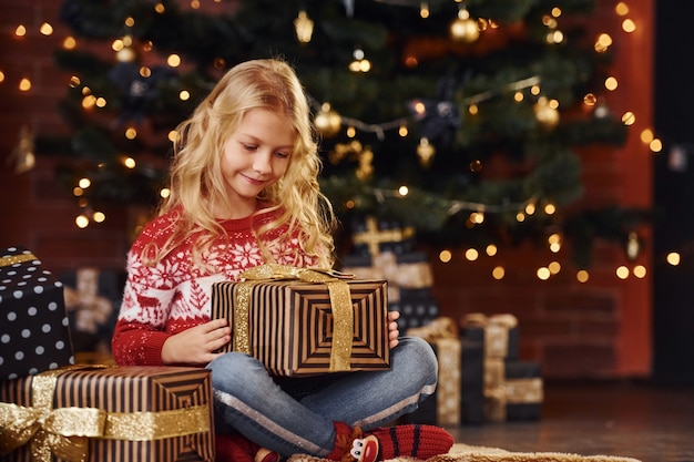 Bambina sveglia con scatole regalo al chiuso per celebrare il capodanno e le vacanze di natale.