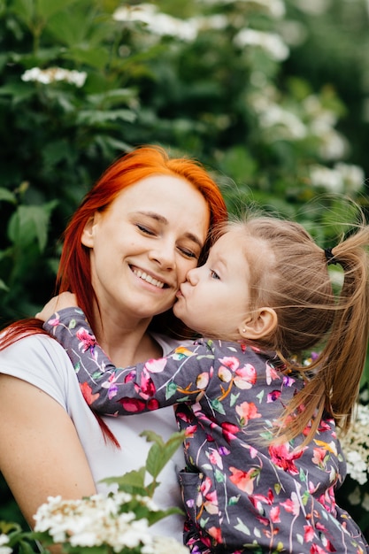 Bambina sveglia con sua madre in un giardino floreale