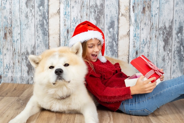 Bambina sveglia con un cane con i cappelli di Babbo Natale