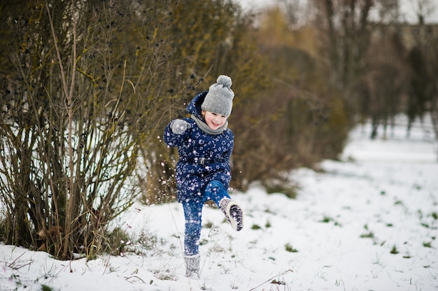 Bambina sveglia divertendosi all'aperto il giorno di inverno.