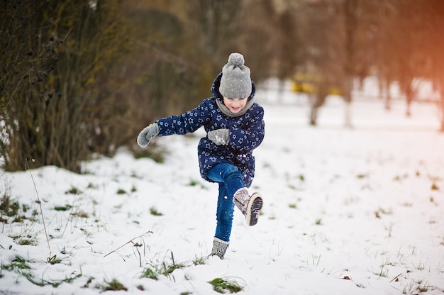 Bambina sveglia divertendosi all'aperto il giorno di inverno.