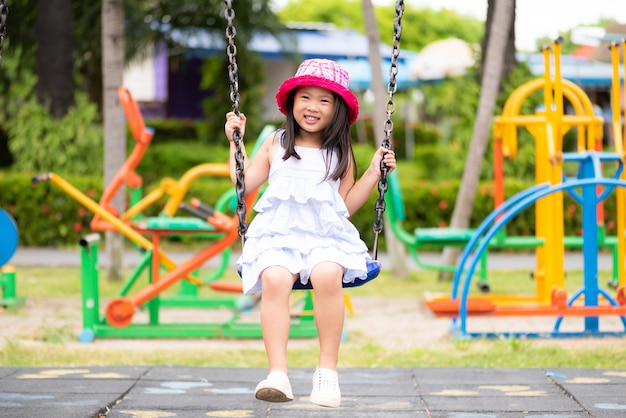 Bambina sveglia divertendosi con l&#39;oscillazione nel parco. Parco giochi per bambini