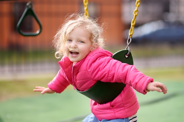 Bambina sveglia divertendosi sul campo da giuoco all&#39;aperto