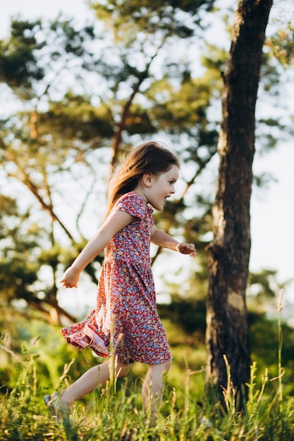 Bambina sveglia felice che corre sull'erba nel parco Felicità