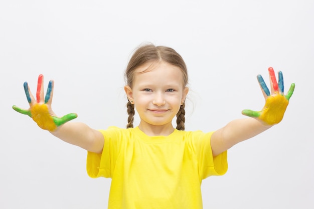 Bambina sveglia felice con le mani dipinte colorate isolate su un concetto di istruzione bianco