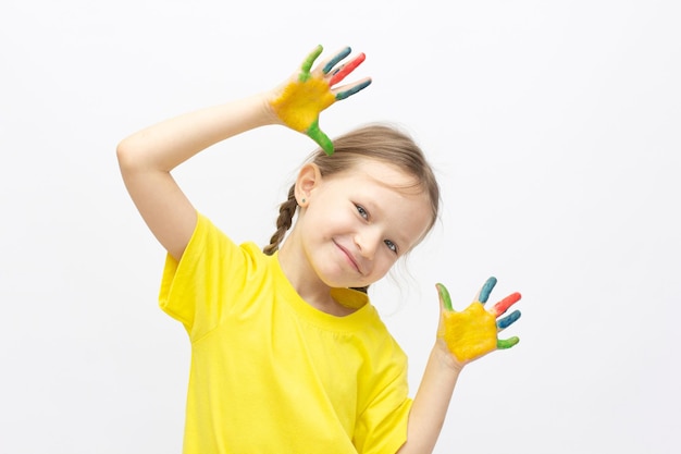 Bambina sveglia felice con le mani dipinte colorate isolate su un concetto di istruzione bianco