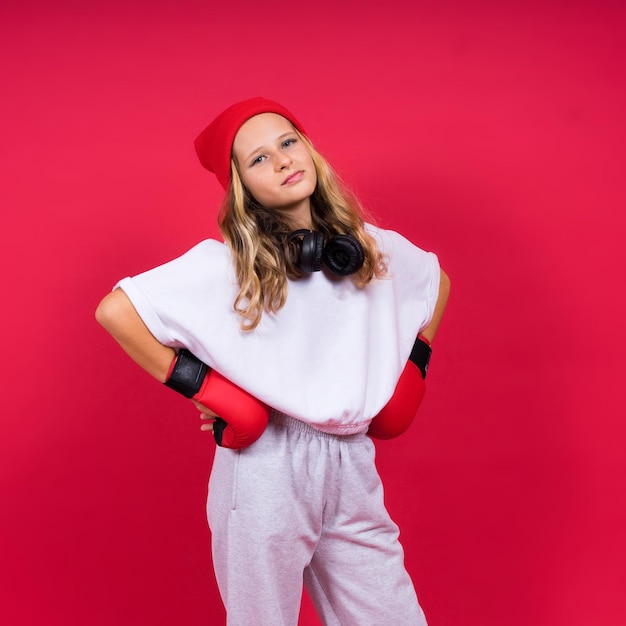 Bambina sveglia in guantoni da boxe su sfondo rosso studio