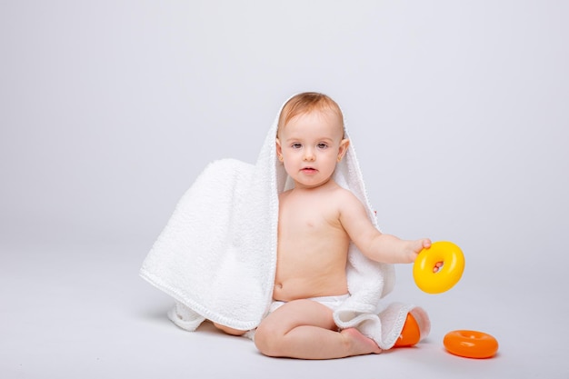 Bambina sveglia in un pannolino che gioca con un giocattolo colorato a piramide isolato su sfondo bianco